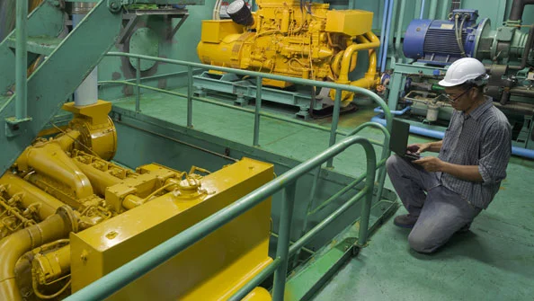 Engenheiro asiático trabalhando na sala de máquinas. Ele usa laptop na inspeção do motor do navio de pesca, conceito de ocupação e tecnologia